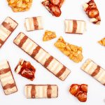 Assorted chocolate and nougat bars with caramelized nuts on a white background.